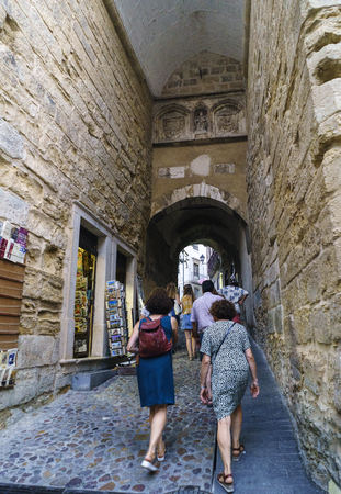 Coimbra, Portugal, August 13, 2018: View of the famous arch called Almedina in the street of the same name in the most central part of the city, on a cobblestone street with irregular cobbles and a very strong slopeのeditorial素材