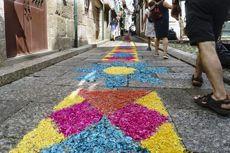 Guimaraes, Braga, Portugal. August 14, 2017: Narrow cobblestone alley with very colorful ornaments formed by small papers in its center. View at ground levelのeditorial素材