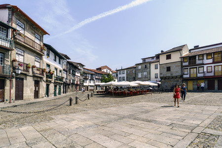 Guimaraes, Braga, Portugal. August 14, 2017: plaza in the center of town with cobblestone floor and gothic stone buildings called Santiago with a bar terrace and touristsのeditorial素材