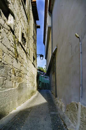Narrow cobblestone alley if people in the center of Porto (Portugal) with facades of stone housesの写真素材
