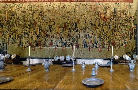 Guimaraes, Portugal. August 14, 2017: Detail of medieval tableware cutlery on the large wooden table in the main hall of the Dukes of Braganza and a large tapestry embroidered in the backgroundのeditorial素材