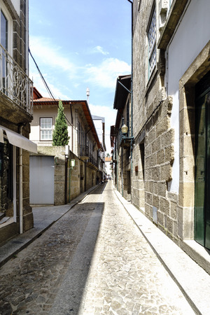 Narrow cobblestone alley with facades of old granite stone houses in the old town called Guimaraes in Portugalのeditorial素材