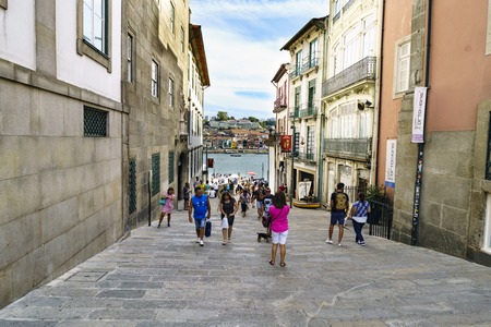 Porto, Portugal. August 12, 2017: Street called de la Alfandega with floor of stone blocks and tourists strolling. In the background the estuary of the Douro Riverのeditorial素材
