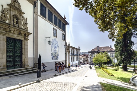 Guimaraes, Portugal. August 14, 2017: Facade of the catholic church called Nossa Senhora do carmo with a mosaic of tiles with the image of the Virgin Mary and Carmen garden with young people walkingのeditorial素材