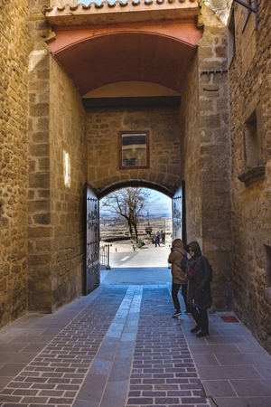 Laguardia, Alava, Spain. March 30, 2018: Puerta deroble medieval granite stone entrance to the village on the street called Paganos seen from the interior of the town, with women coming out of itのeditorial素材