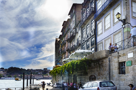 Porto, Portugal. August 12, 2017: Houses located on the banks of the estuary of the river Douro with terraces of bars and people drinking and walkingのeditorial素材