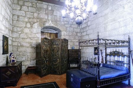 Guimaraes, Portugal. August 14, 2017: Medieval-type bedroom of the Dukes of Braganza in its palace with four-poster bed, medieval furniture and granite stone wallsのeditorial素材