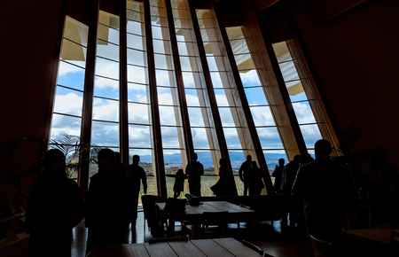 Backlight of the wine tasting room in a wine cellar in La Rioja (Spain) with people in the dark drinking wine and eating typical sausages. Vineyards are seen and the town of Laguardiaの写真素材