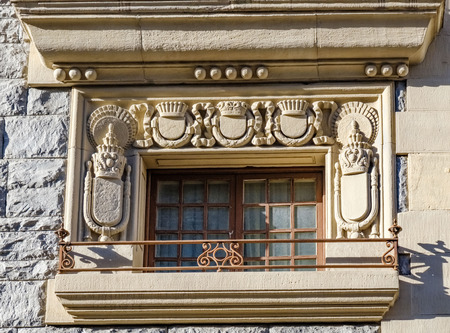 Detail of a window surrounded by shields carved in stone in an old granite stone houseの写真素材