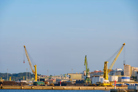 three heavy cranes, two yellow and one green used for loading merchant ships in the port of La Coruna in Spainの写真素材