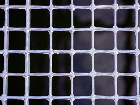 Silver metallic grating of squares on a black background of the waters of a riverの写真素材