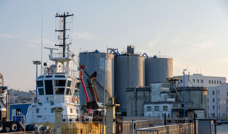 Silos and port facilities in the port of the city of La Coruna in Spain. In the foreground the bridge of a tugboatの写真素材