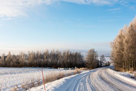 Icy road in countryside on a winter day with some clouds in the skyの写真素材