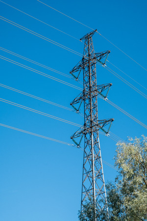 High voltage electrical power line pylon with blue sky as background on a sunny dayの写真素材