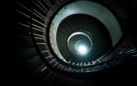Spiral staircase in a dark room with a light on itの素材