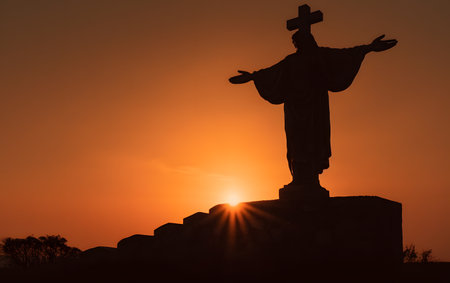Silhouette of Jesus Christ statue at sunset in the countryside.の素材