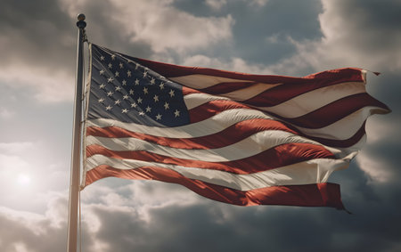 American flag waving in the wind against a cloudy sky with sun raysの素材