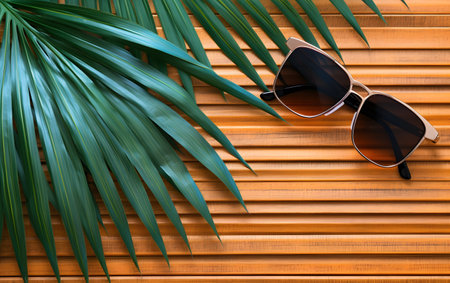 Sunglasses and palm leaves on wooden background. Summer holiday conceptの素材