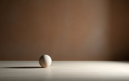 White ball on a wooden table and a brown wall in the backgroundの素材