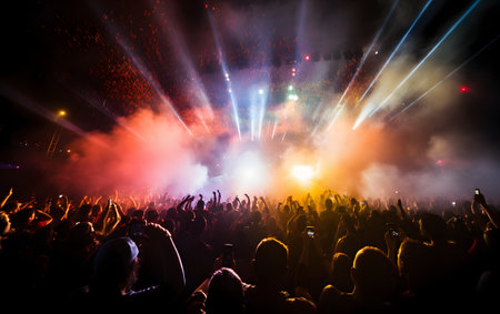 Crowd at concert with bright stage lights and smoke on the backgroundの素材