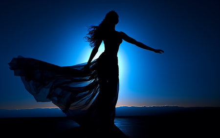 Silhouette of a beautiful woman dancing on the beach at sunsetの素材