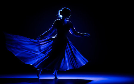 silhouette of a beautiful girl in a blue dress dancing on a black backgroundの素材