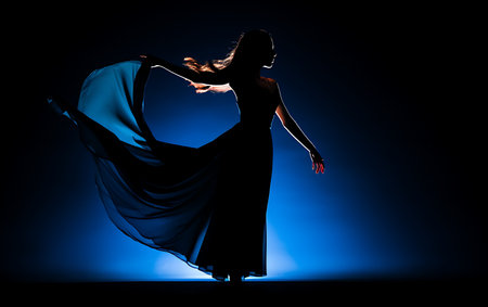 Silhouette of young woman dancing flamenco on dark backgroundの素材