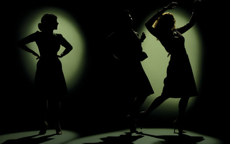 Silhouette of two women dancing in dark room with spotlight.の素材