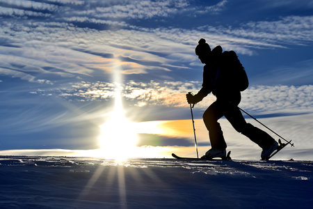 Silhouette of a man skiing in the mountains at sunset.の素材