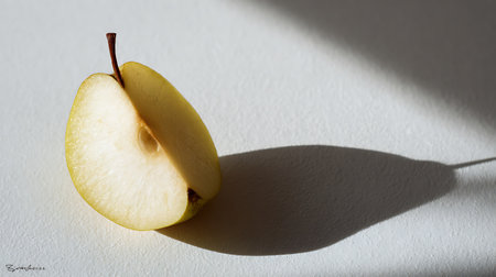 Half of a ripe yellow apple on a white background with shadows.の素材