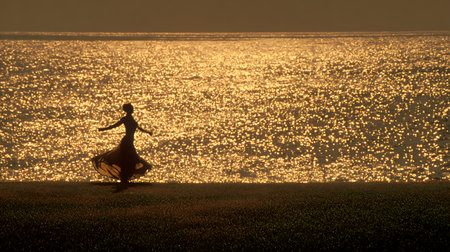 Silhouette of a woman dancing in the beach at sunset.の素材