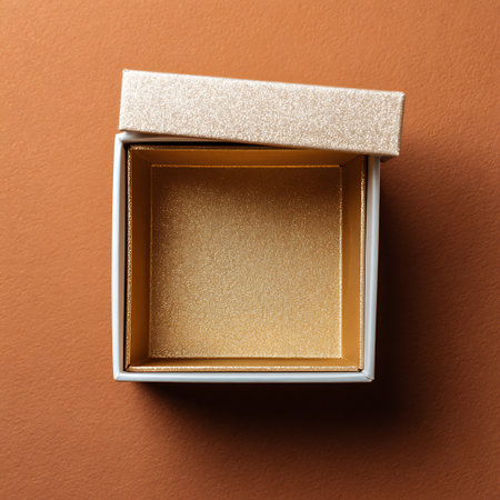 Opened golden gift box on orange background. Top view. Flat lay.の素材