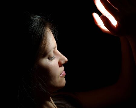 Beutiful girl with light in hands in the black backgroundの写真素材