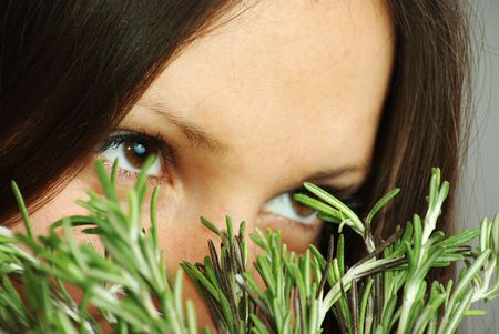 Beatutiful girl with bright eyes sniffing rosemaryの写真素材