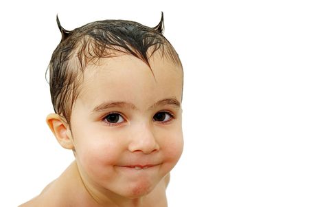 Little boy with horns made out of wet hair watching in the camera with sly smile, isolated on whiteの写真素材