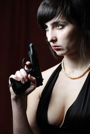 Woman in evening dress and pearl necklace holds gunの写真素材