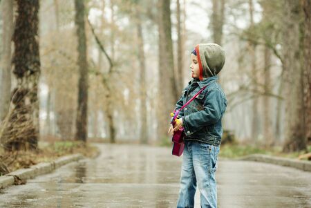 Little boy plays guitar in rainy parkの写真素材