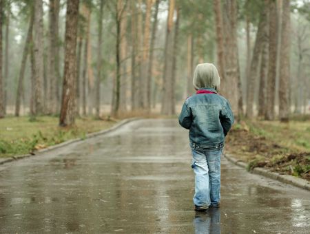 Little boy walks the long rainy road in the forestの写真素材