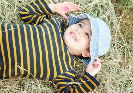 Playful boy lying on the hay on summer dayの写真素材