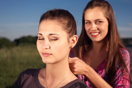 Girlfriends weaving the braid outdoors on the meadowの写真素材