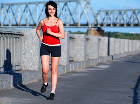 Woman jogging at the embankment in the sunny day