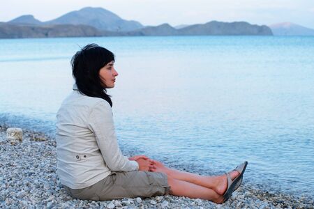 Single woman sitting on the empty beach relaxingの写真素材