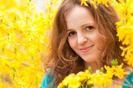 Portrait of redhead woman in yellow bloom flowers with dandellionsの写真素材