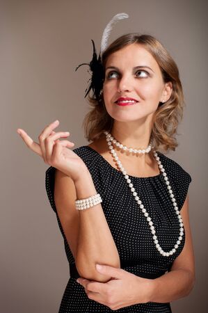 Retro woman in dress and pearl beads with feather pointing upwards