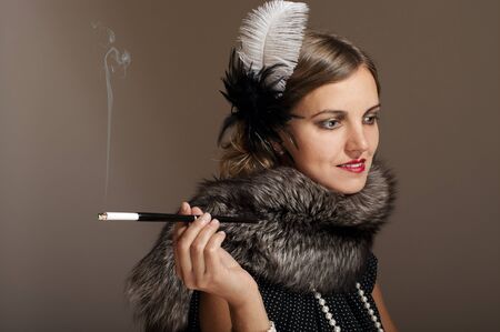 Retro woman in fur and feather with cigarette mouthpiece の写真素材