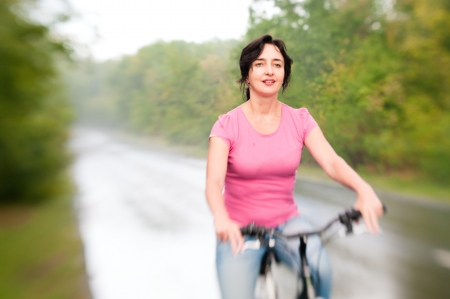 Woman tired with bike on the rainy forest road  Lensbaby effectの写真素材