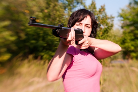 Woman aiming rifle in the sunny summer forest  Lensbaby effectの写真素材