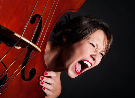 Girl face screaming by double bass closeupの写真素材