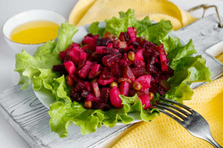Vinaigrette on a white background. Traditional Russian vegetable salad with red beets on a plate. Vegetarian dish on a yellow napkin.の写真素材