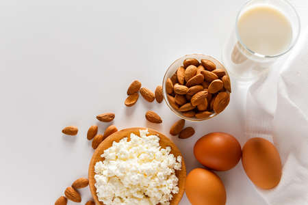Rustic homemade protein balanced diet food. Cottage cheese, eggs, nuts and milk on a white...